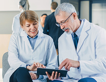 Doctors sitting together looking at tablet and pointing at it.